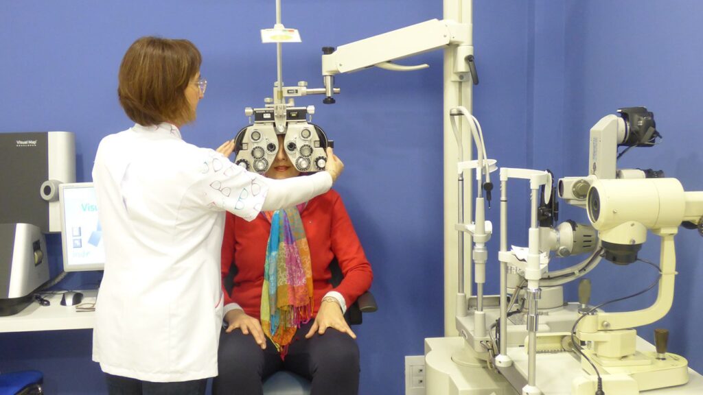 Óptica-optometrista graduando la vista con foróptero en la óptica LentiAudio de Montijo